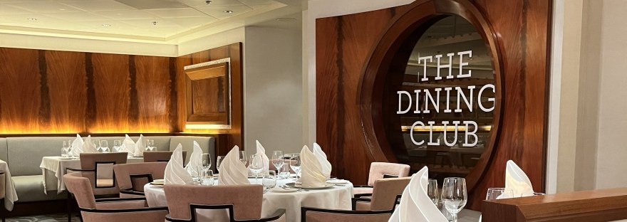 The Dining Club sign on a glass background with seating in the foreground