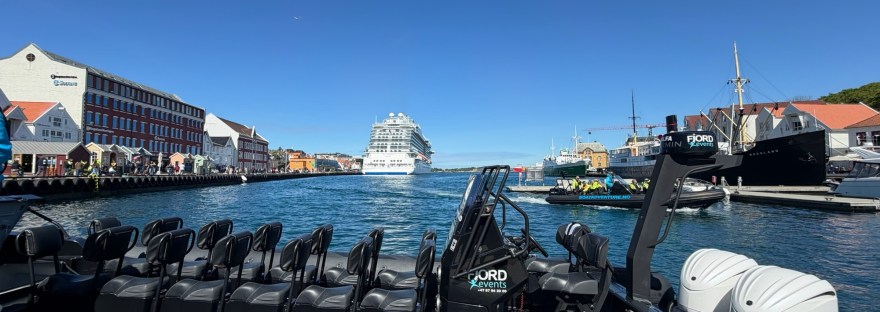 A rigid inflatable boat (RIB) moored at the dock in Stavanger, Norway, with the Sky Princess cruise ship docked in the background.